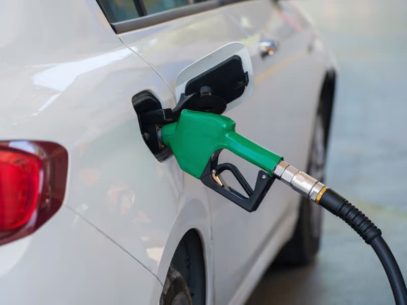 Grüne Zapfpistole im Tankstutzen eines weissen Autos