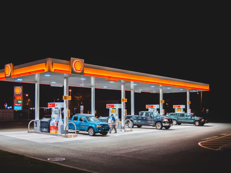 Hell beleuchtete Tankstelle bei Nacht mit Fahrzeugen an den Zapfsäulen