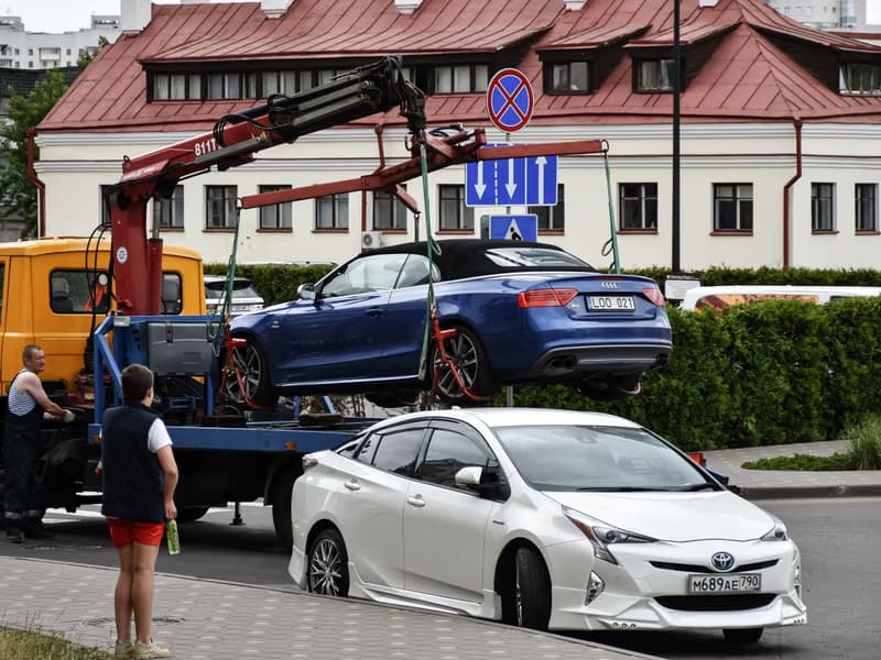 Abschleppkran hebt ein blaues Auto vom Strassenrand