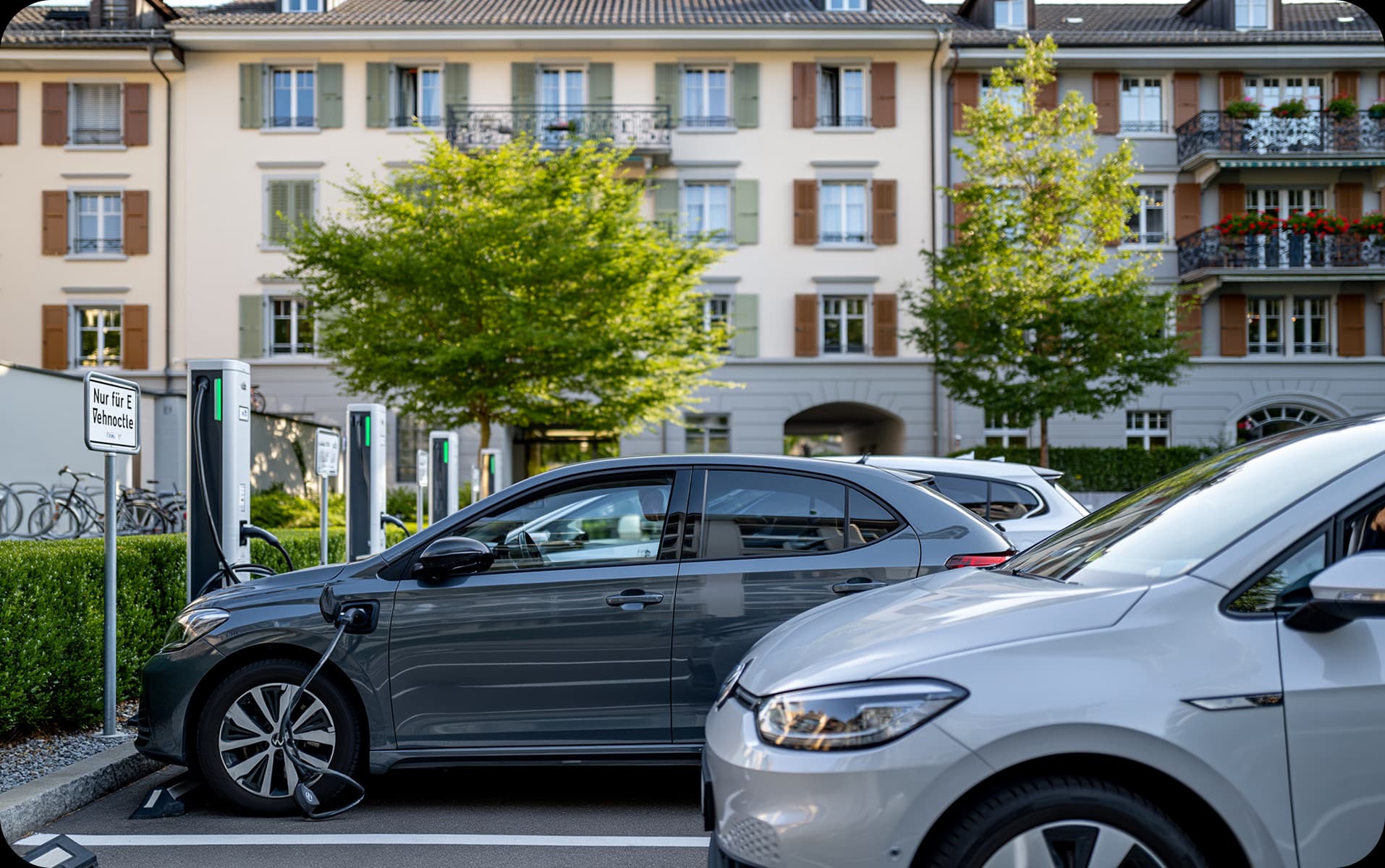 Electric vehicles at charging stations in front of a residential building